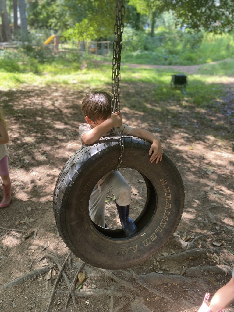 boy struggling to climb onto tire swing